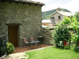 un patio con 2 sillas y una mesa en un edificio de piedra en El Castillo, en Boltaña