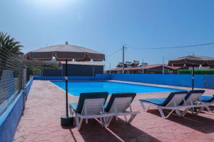 a swimming pool with two chairs and an umbrella at LOCA BEACH in Taghazout
