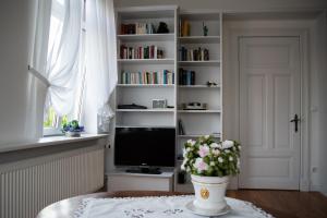 un salon avec une télévision et un vase de fleurs dans l'établissement Villa Noorhus, à Eckernförde