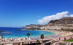 una spiaggia con una folla di persone e l'oceano di APT with terrace facing Amadores beach ad Amadores