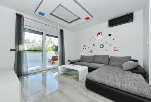 ein Wohnzimmer mit einer Couch und einer Uhr an der Wand in der Unterkunft Villa Lily ZadarVillas in Privlaka