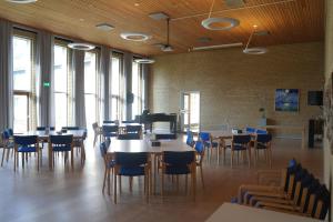 un comedor con mesas, sillas y ventanas en Emmaus Hostel, en Haslev