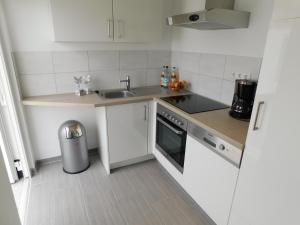 a white kitchen with a sink and a stove at Hafenkieker in Greetsiel