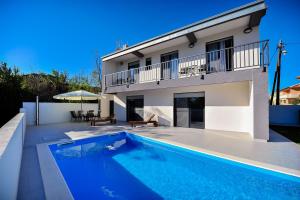 ein Haus mit einem Swimmingpool vor einem Haus in der Unterkunft Villa Lily ZadarVillas in Privlaka