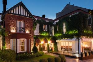 a large brick house with a garden in front of it at Altos de Guemes Hotel in Mar del Plata