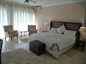 1 dormitorio con 1 cama grande y 2 sillas en Heatherdale Guesthouse & Shuttle Services en Pretoria