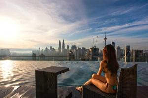 a woman in a bikini sitting next to a swimming pool at Maxhome@Regalia suite residence. KL in Kuala Lumpur
