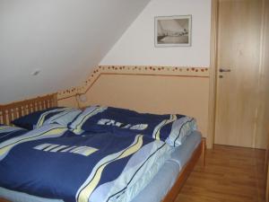 a bed with a blue comforter in a bedroom at Ferienwohnung Vieth in Filsum