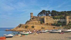 
a beach filled with lots of boats on a sunny day at Hotel Don Juan Tossa in Tossa de Mar
