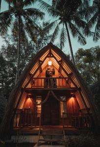 a tree house with a balcony and two palm trees at Island View Bar & Bungalow in Gili Islands