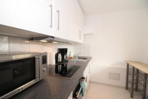a kitchen with white cabinets and a black counter top at Waldhof Residenz in Offenbach