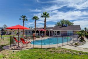 a house with a swimming pool with two chairs and a red umbrella at Villa Umber in Las Vegas