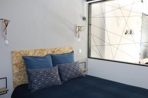 een slaapkamer met een bed met blauwe kussens en een raam bij Lagos Beach 59A in Lagos