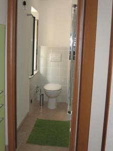 a bathroom with a toilet and a green rug at Zephyros - VIVERE IL MARE E LA STORIA DEL BORGO in Santa Caterina dello Ionio
