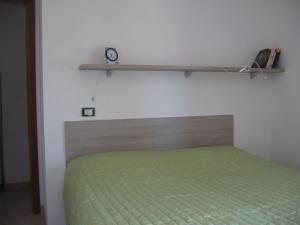 a bedroom with a green bed and a clock on a wall at Zephyros - VIVERE IL MARE E LA STORIA DEL BORGO in Santa Caterina dello Ionio