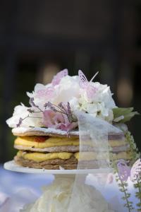 un gâteau avec des fleurs et des papillons en haut dans l'établissement Ristolocanda Grani Di Pepe, à Flaibano