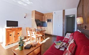 a living room with a red couch and a kitchen at Résidence Goélia Le Sornin in Autrans