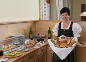 a woman in a kitchen holding a basket of bread at Gasthof Hofbauer in Breitenau am Hochlantsch