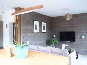 a living room with a couch and a tv on a brick wall at Maison à deux pas de l'océan in Biscarrosse-Plage