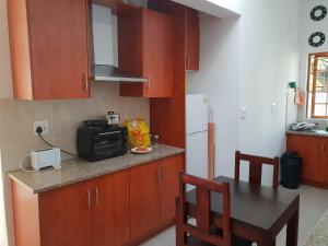 a kitchen with wooden cabinets and a table with a microwave at Fama Lodge Single Rooms in Cape Town