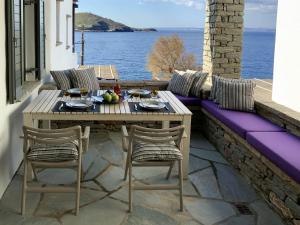 a table and chairs on a patio with a view of the water at Aqua Blue, only 100 meters from the beach of Gialiskari in Ioulis