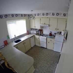 a small kitchen with white appliances and a window at Cosy Keel Cottage in Keel