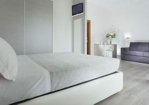 a white bedroom with a white bed and a couch at Hotel Sammaritani in Rimini