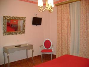um quarto com uma mesa, uma cadeira vermelha e uma secretária em Santa Cruz em Los Palacios y Villafranca