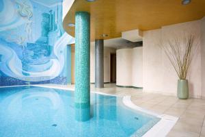 a large swimming pool with two columns in a building at Promenáda Romantic Hotel in Karlovy Vary