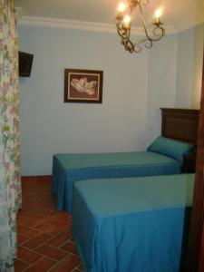 um quarto com duas camas azuis e uma foto na parede em Santa Cruz em Los Palacios y Villafranca