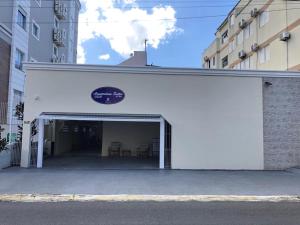 a white building with a garage with chairs in it at HANNA Flat Amsterdam in Florianópolis