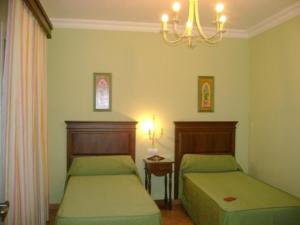 a bedroom with two beds and a chandelier at Santa Cruz in Los Palacios y Villafranca