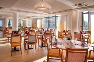 un restaurant avec des tables et des chaises en bois ainsi que des fenêtres dans l'établissement DOMITYS LES SABLES D'OR, à Villeneuve-le-Roi