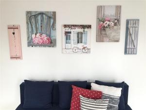four pictures hanging on a wall above a couch at Marea Apartamenty Ustka in Ustka