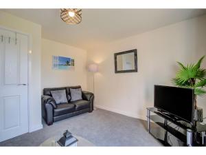 a living room with a couch and a flat screen tv at Newly built, splendid house for 5 in Manchester! in Manchester