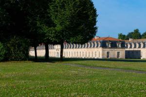 een groot wit gebouw met bomen in het gras bij Cit' Hotel de France in Rochefort