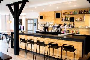 a bar in a restaurant with black bar stools at Logis Hôtel La Bastide des Oliviers in Monflanquin