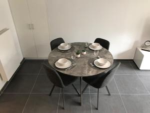 a dining room table with black chairs and a table with plates at Residentie Sorrento in Middelkerke