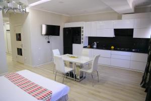 a kitchen with a white table and white chairs at Lux Bishkek Apartment in Bishkek