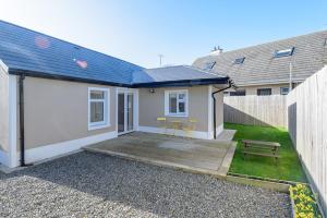 a small white house with a wooden patio with a bench at Garra Cottage in Drogheda
