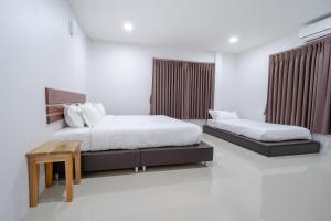 a bedroom with two beds and a table at Myrrh Hotel Chanthaburi in Chanthaburi