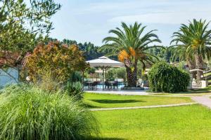 a garden with palm trees and a table and chairs at Iris Hotel in Siviri