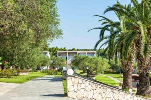 a park with palm trees and a stone wall at Iris Hotel in Siviri