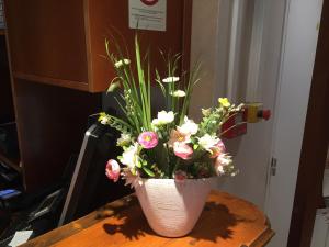 マルセイユにあるオテル デュ シュド ヴィユ ポールのテーブルの上に花が咲き誇る白い花瓶