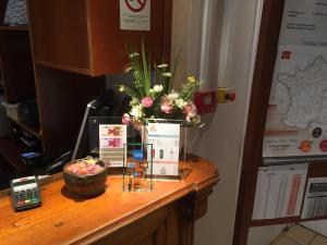 un escritorio de madera con un jarrón de flores. en Hôtel du Sud Vieux Port, en Marsella