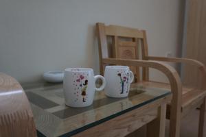 two coffee mugs sitting on a table next to a chair at Camellia Hotel in Thanh Hóa