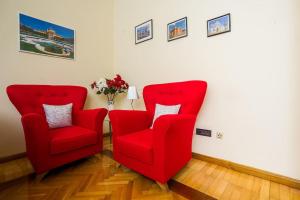 two red chairs in a room with a vase of flowers at Golden Star in Zagreb