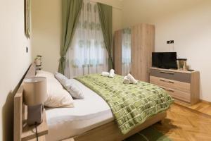 a bedroom with a bed with a green blanket and a tv at Golden Star in Zagreb