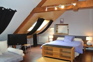 um quarto com uma cama, uma televisão e um sofá em L 'Annexe em Lohéac