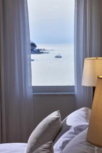 a bed with a window with a view of the ocean at Poseidonion Grand Hotel in Spetses